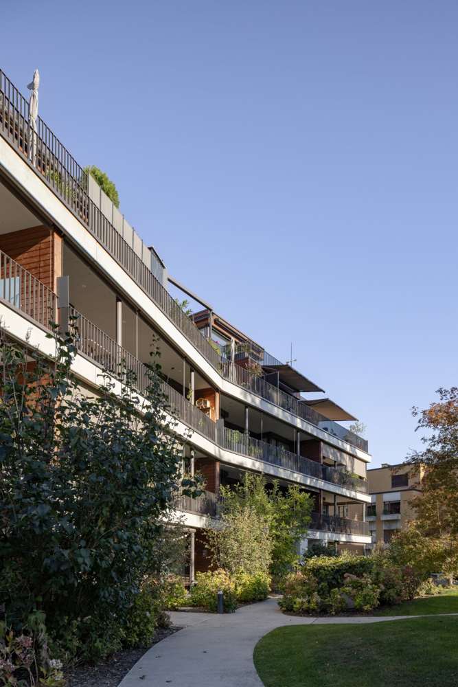 Gartenseite: die durchlaufenden Brüstungsbänder und Fallarmmarkisen entlang des geknickten Baukörpers.