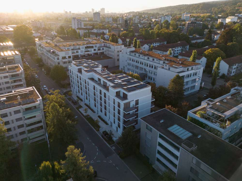 Blick gegen Westen: Haus 40 an der Unterfeldstrasse, die Balkone zur Hofseite, die Attikageschosse mit Sonnenstoren; im Hintergrund die Stadt.
